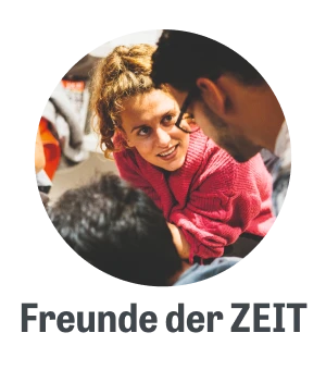 Junge Frau in einem rosa Pullover, die engagiert mit zwei Personen spricht, während sie in einer entspannten Umgebung sitzen.